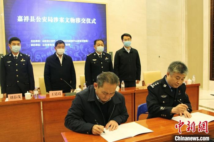山東博物館館長(zhǎng)鄭同修和嘉祥縣人民政府副縣長(zhǎng)、公安局局長(zhǎng)趙健簽署移交協(xié)議。　趙曉 攝
