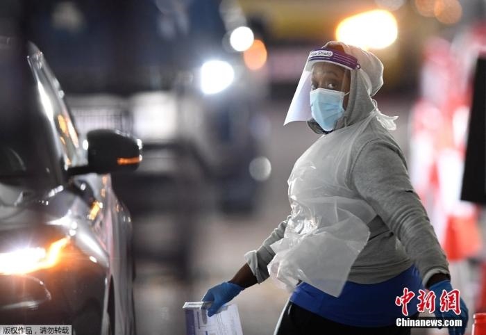 當(dāng)?shù)貢r間12月18日，英國政府公布的數(shù)據(jù)顯示，當(dāng)天英國新增奧密克戎毒株感染病例10059例。鑒于奧密克戎毒株感染病例激增，住院人數(shù)不斷上升，倫敦市長宣布倫敦進(jìn)入“重大事故”狀態(tài)。圖為倫敦的一個免下車檢測中心，一名醫(yī)務(wù)工作者正準(zhǔn)備對司機(jī)進(jìn)行核酸檢測。