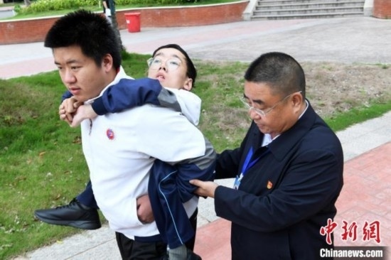 朱金祥背著鐘華強去教室上課的路上，也經(jīng)常碰到值班的校領(lǐng)導(dǎo)和老師前來搭把手。 卓忠偉 攝