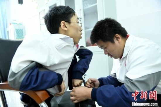 江西省南康中學北校區(qū)的高三學生朱金祥(右)正在給鐘華強(左)系好鞋帶。 卓忠偉 攝