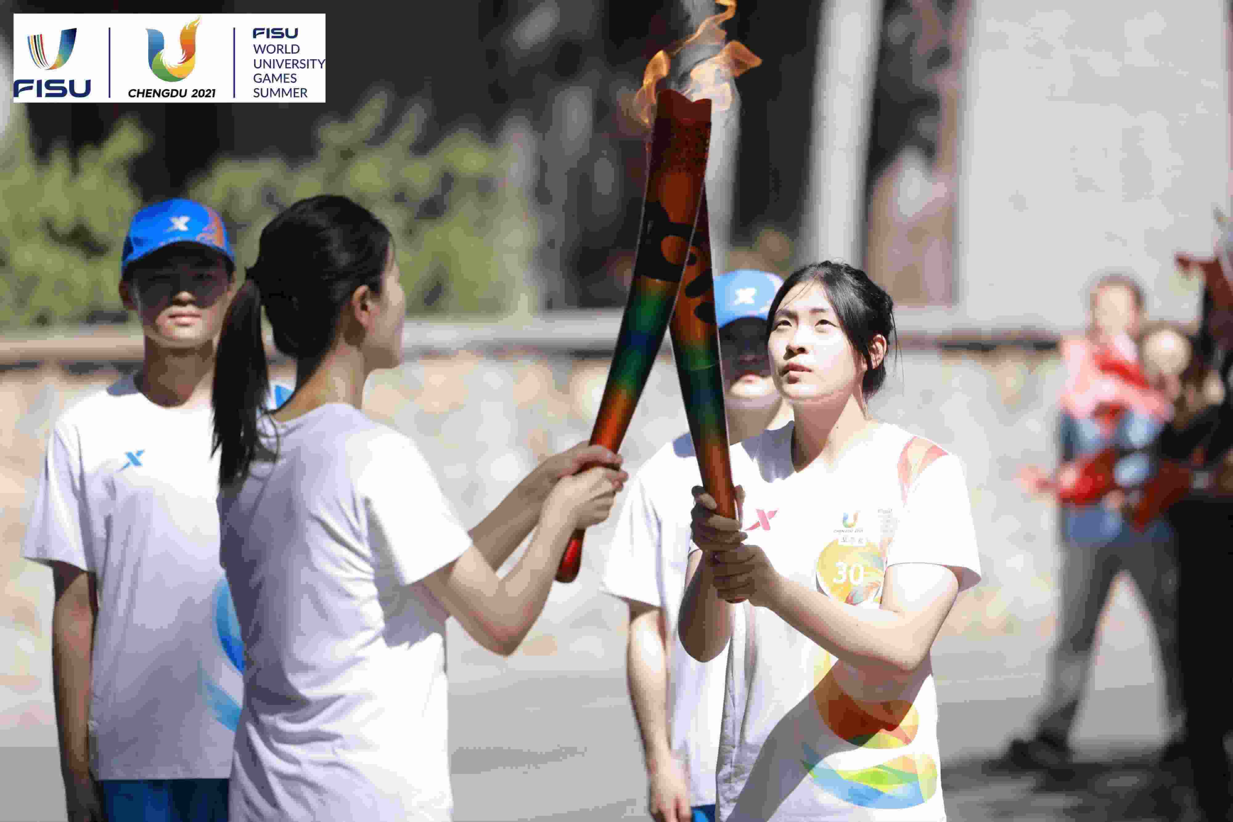 兩名大運(yùn)會(huì)火炬手進(jìn)行火炬?zhèn)鬟f。 圖片來源：成都大運(yùn)會(huì)執(zhí)委會(huì)供圖