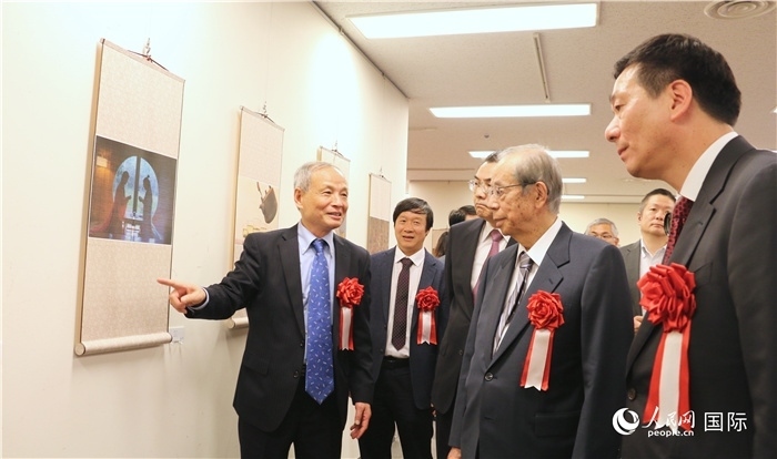 “湖州印象”攝影展主創(chuàng)、世界華人攝影協(xié)會(huì)副會(huì)長馮學(xué)敏向吳江浩大使、福田康夫前首相等嘉賓介紹展出作品。（人民網(wǎng) 許可攝）