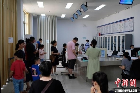 圖為在戶籍辦證廳內(nèi)排隊等待的家長和孩子。劉俊聰 攝