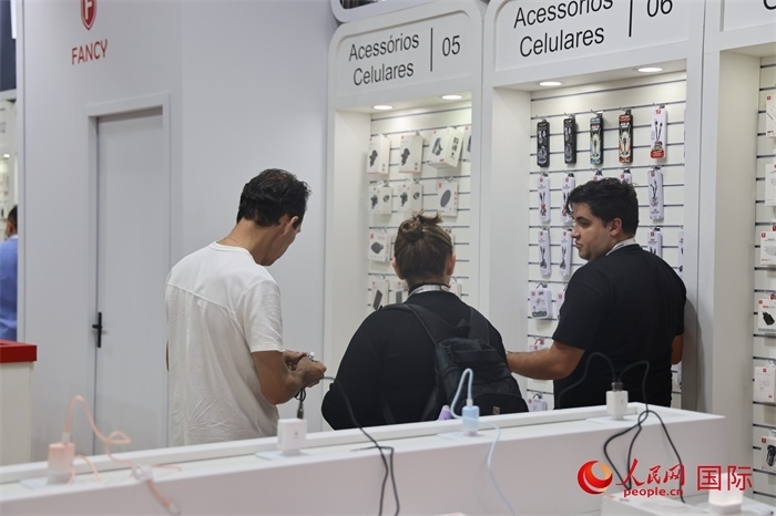 幾名參觀者在一個(gè)展臺(tái)前了解手機(jī)配件。（人民網(wǎng)記者 時(shí)元皓攝）