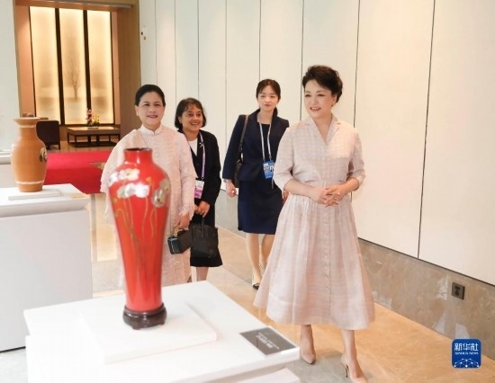 7月27日下午，國家主席習(xí)近平夫人彭麗媛在四川成都會見陪同印度尼西亞總統(tǒng)佐科來華出席第31屆世界大學(xué)生夏季運動會開幕式并訪華的總統(tǒng)夫人伊莉亞娜。這是彭麗媛和伊莉亞娜欣賞成都特色非遺工藝品。新華社記者 丁林 攝