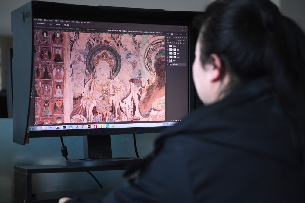 敦煌研究院文物數(shù)字化保護(hù)團(tuán)隊(duì)圖像處理人員年海麗在拼接壁畫圖像（2023年4月25日攝）。數(shù)字化探索為莫高窟的保護(hù)與傳承開辟了全新路徑，數(shù)字技術(shù)讓敦煌文物走出洞窟，跨出國門，走向“永久保存、永續(xù)利用”。新華社記者 陳斌 攝