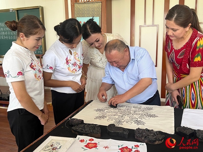 國家級(jí)非物質(zhì)文化遺產(chǎn)模戳印花布技藝傳承人吾吉阿西木?吾舒爾展示模戳印花布的制作過程。人民網(wǎng)記者 常雪梅攝