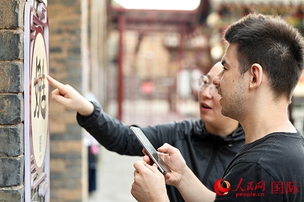 選手安德烈（俄羅斯）在老師指導(dǎo)下學(xué)習(xí)墻壁上張貼的生僻字。人民網(wǎng) 盧鵬宇攝