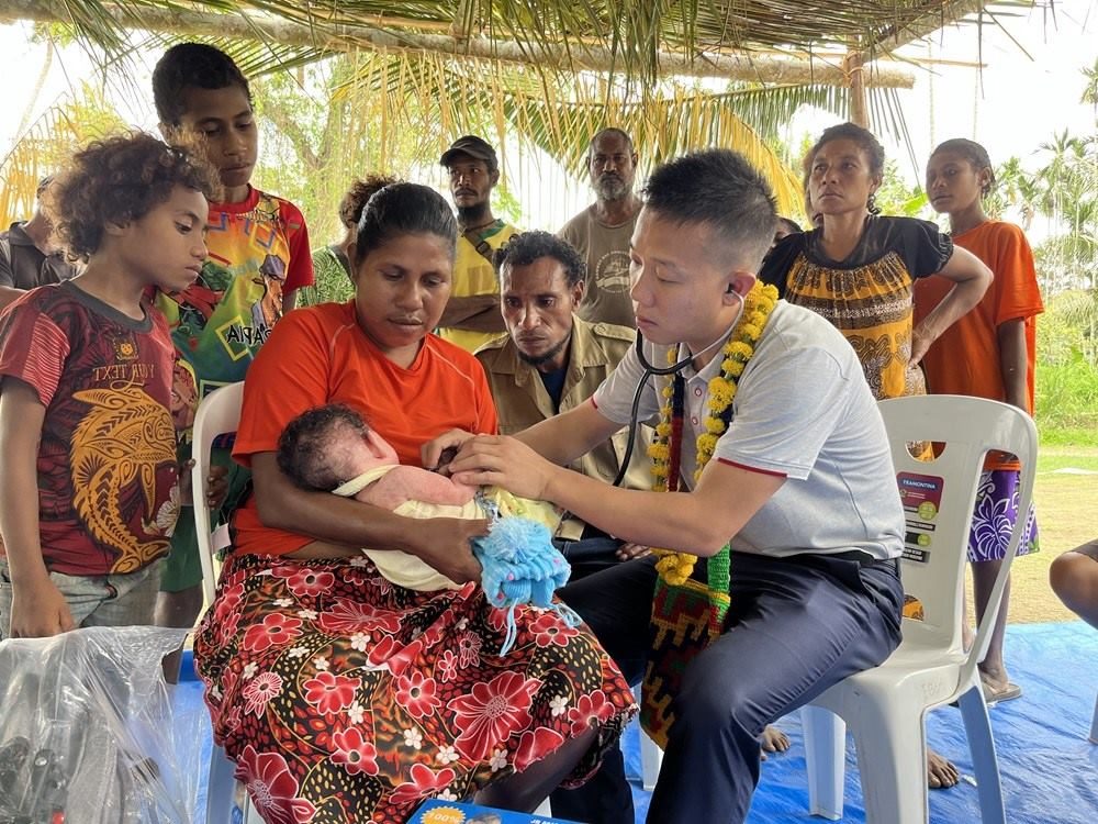 2023年8月5日，在巴布亞新幾內(nèi)亞中央省的一個村莊里，第12批援巴新中國醫(yī)療隊副隊長、新生兒科副主任醫(yī)師劉振球為當(dāng)?shù)貗雰郝犜\檢查。新華社發(fā)（第12批援巴新中國醫(yī)療隊供圖）