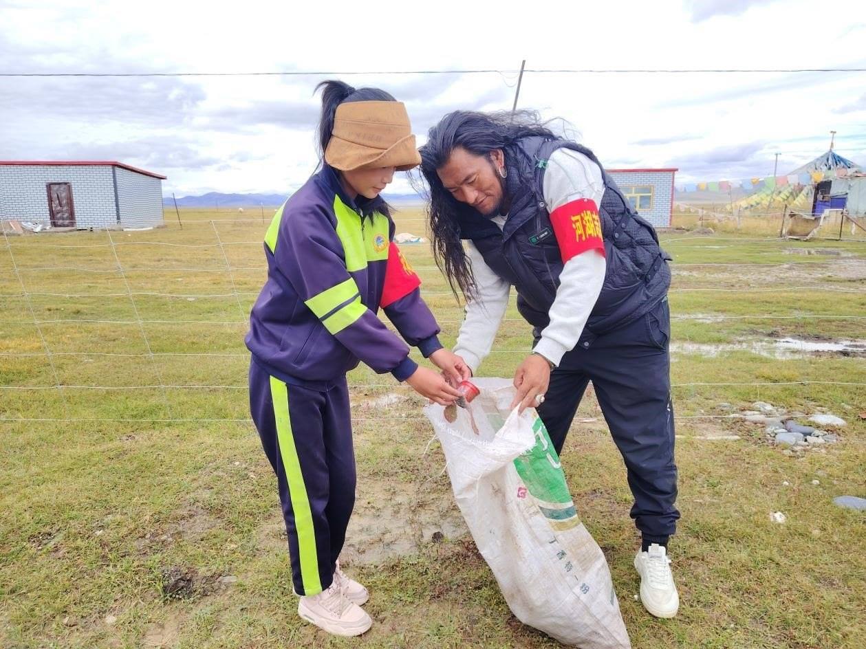 玉樹州稱多縣珍秦鎮(zhèn)河湖志愿者才培和他女兒更求拉毛在清掃垃圾。受訪者供圖