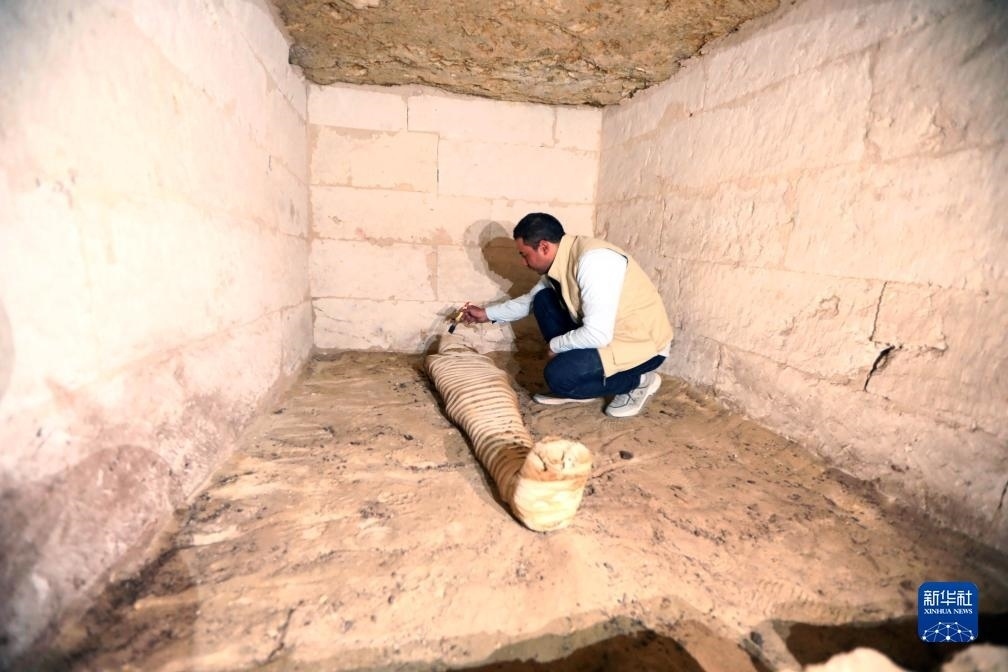 10月15日，在埃及明亞省考古現(xiàn)場，考古人員清理一座石鑿墓中的木乃伊。新華社發(fā)（艾哈邁德·戈馬攝）