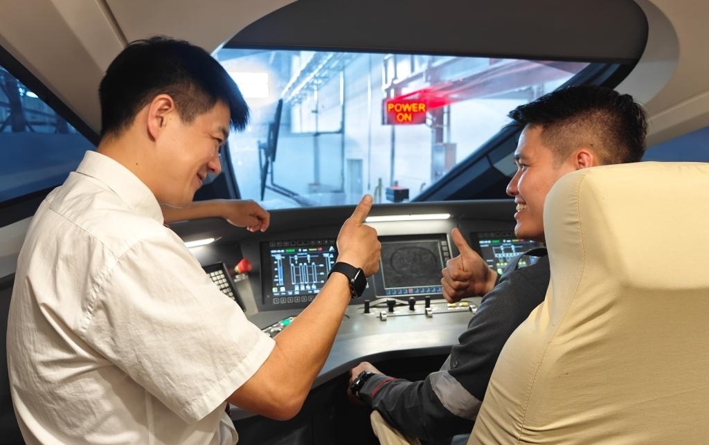 8月25日，在印度尼西亞萬隆的雅萬高鐵德卡魯爾動車所內(nèi)，中國師傅穆振（左）在向印尼火車司機塞蒂亞萬講解動車組出庫前的上電作業(yè)。