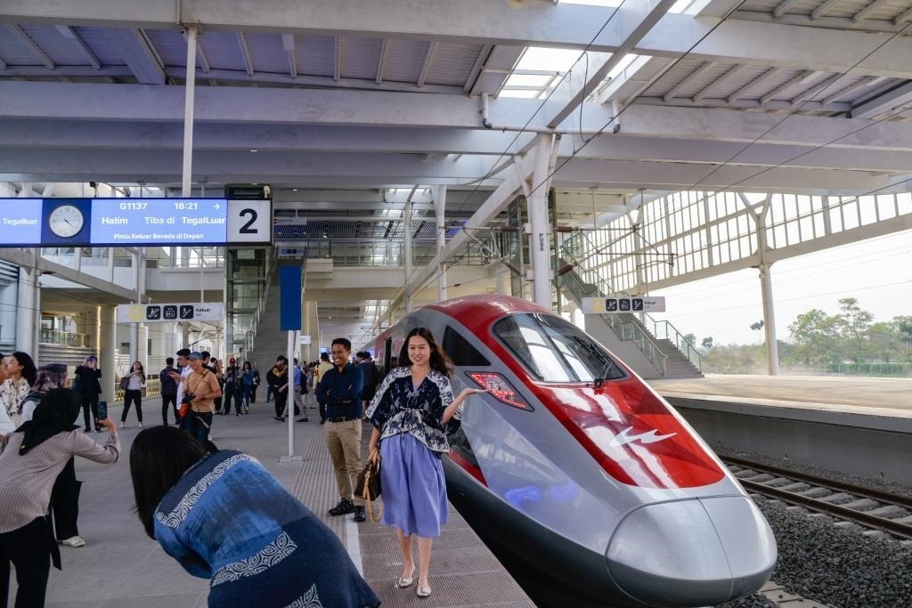 10月17日，在印度尼西亞萬隆德卡魯爾站，乘客在站臺上和雅萬高鐵高速動車組列車合影。