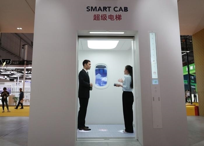 11月5日，工作人員（右）在第六屆進(jìn)博會上向參觀者介紹奧的斯公司全新推出的超級電梯。