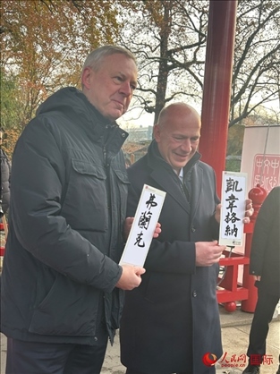 柏林市長韋格納（右）、動物園監(jiān)事會主席布魯克曼（左）手持中國文化中心工作人員現(xiàn)場手書的中文名字。人民網記者 徐馨攝