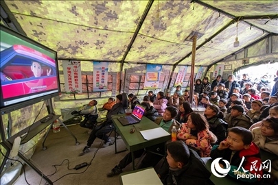 12月22日，在積石山縣大河家鎮(zhèn)大河村安置點(diǎn)，陸軍76集團(tuán)軍某旅搭建的“臨時(shí)學(xué)?！眱?nèi)，小朋友正在看動(dòng)畫片。人民網(wǎng)記者 翁奇羽攝