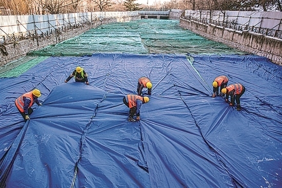 1月3日，房山區(qū)東風(fēng)街道，工人正在修復(fù)的河道內(nèi)給混凝土鋪設(shè)保溫布。