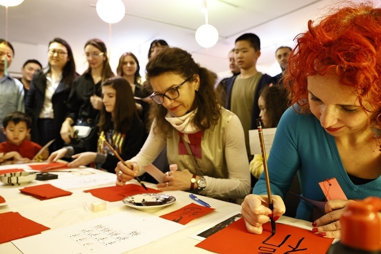 羅馬尼亞觀眾學(xué)習(xí)用毛筆寫“?！弊帧Ｖ袊?guó)文化中心供圖