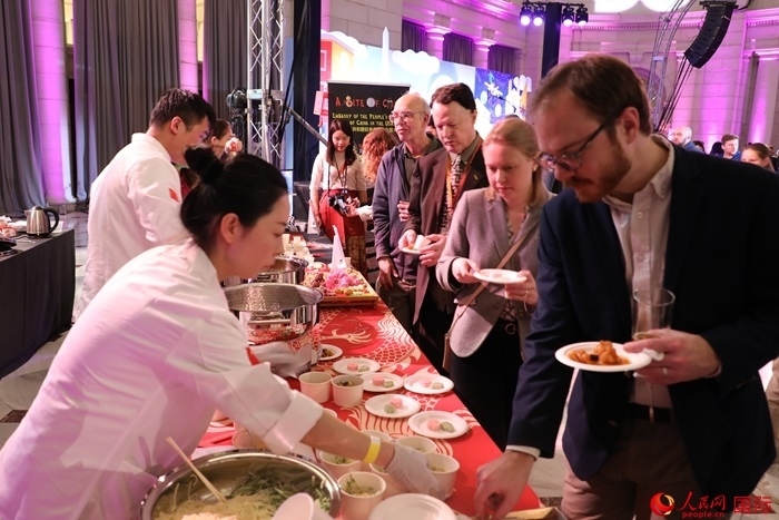 當?shù)貢r間3月7日晚，華盛頓聯(lián)合車站廣場舉行駐美使團“使館主廚挑戰(zhàn)賽”。圖為當?shù)孛癖娫谥袊古_前體驗中國美食。人民網(wǎng)記者 李志偉攝