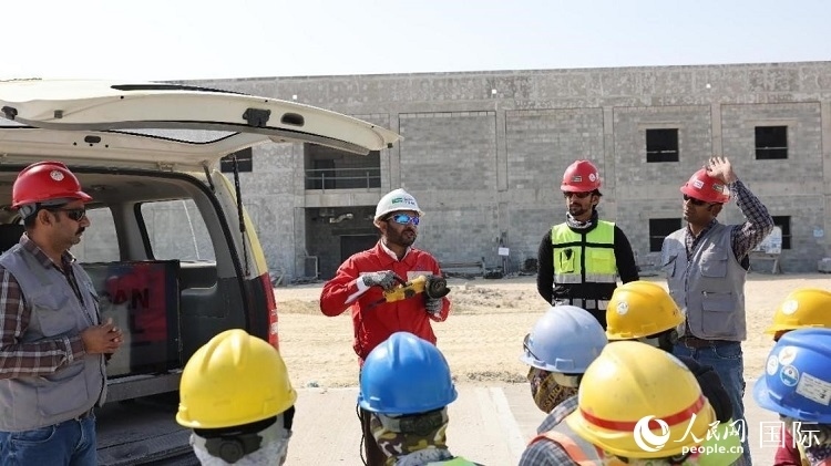 穆薩瓦爾(圖中紅衣人）現(xiàn)場(chǎng)演示工具操作規(guī)范。人民網(wǎng)記者 管克江攝