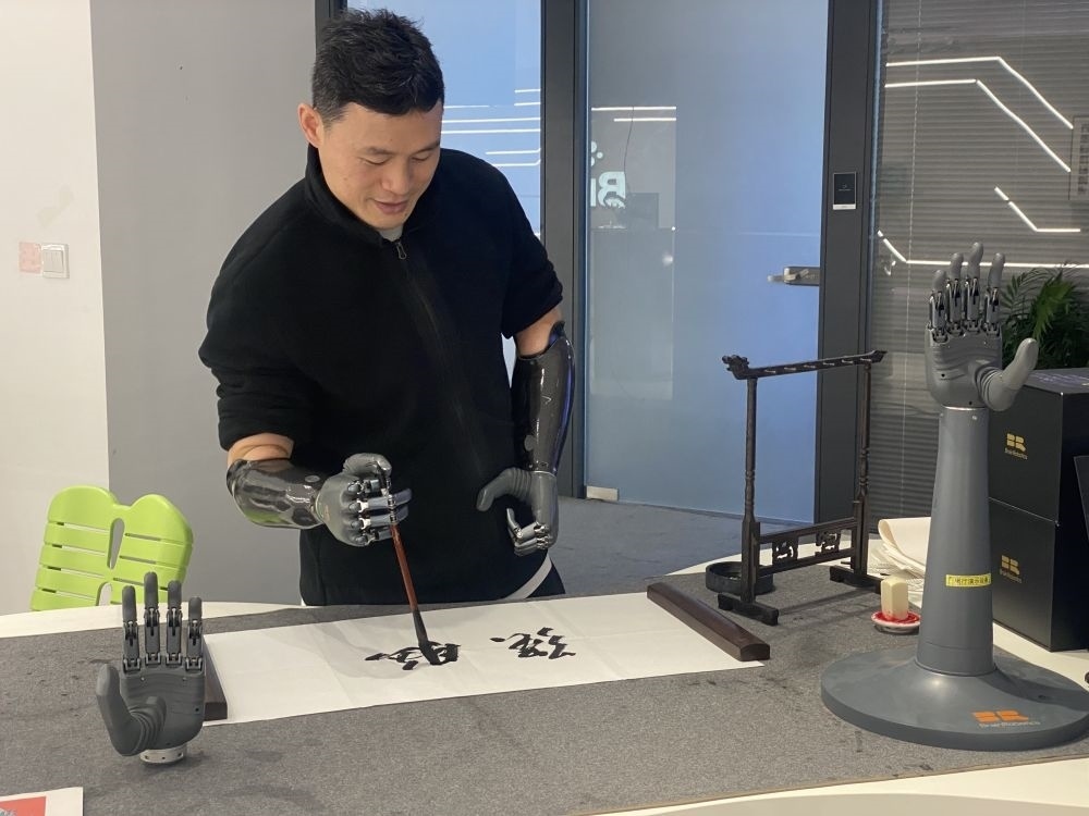 2024年3月29日，在浙江強(qiáng)腦科技有限公司展廳內(nèi)，失去雙手的產(chǎn)品體驗(yàn)官倪敏成依靠智能仿生手寫毛筆字。新華社記者 魏一駿 攝