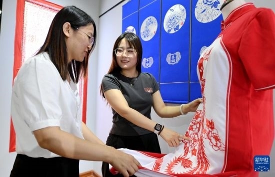 5月31日，在衡水市阜城縣一家剪紙工作室，游客在觀賞帶有剪紙?jiān)氐钠炫邸? width=