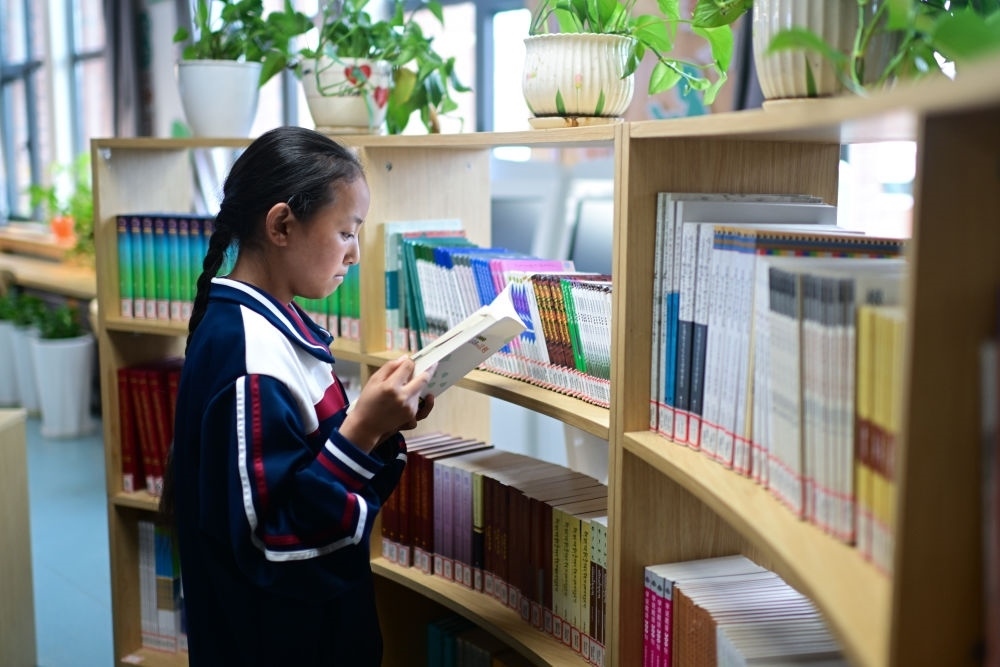 6月18日，果洛西寧民族中學(xué)學(xué)生尼東拉毛在圖書室看書。