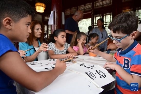 7月4日，在馬耳他桑塔露琪亞市的中國古典園林“靜園”，人們體驗(yàn)中國書法。新華社發(fā)（喬納森·博格 攝）
