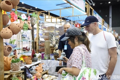 游客在蘭納博覽會特色展位上選購工藝品。人民網(wǎng)記者楊一攝