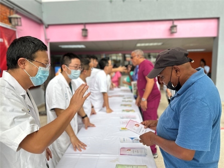 援圭醫(yī)療隊(duì)隊(duì)員們在啟動儀式上為當(dāng)?shù)孛癖姺职l(fā)宣傳手冊。中國援助圭亞那醫(yī)療隊(duì)供圖