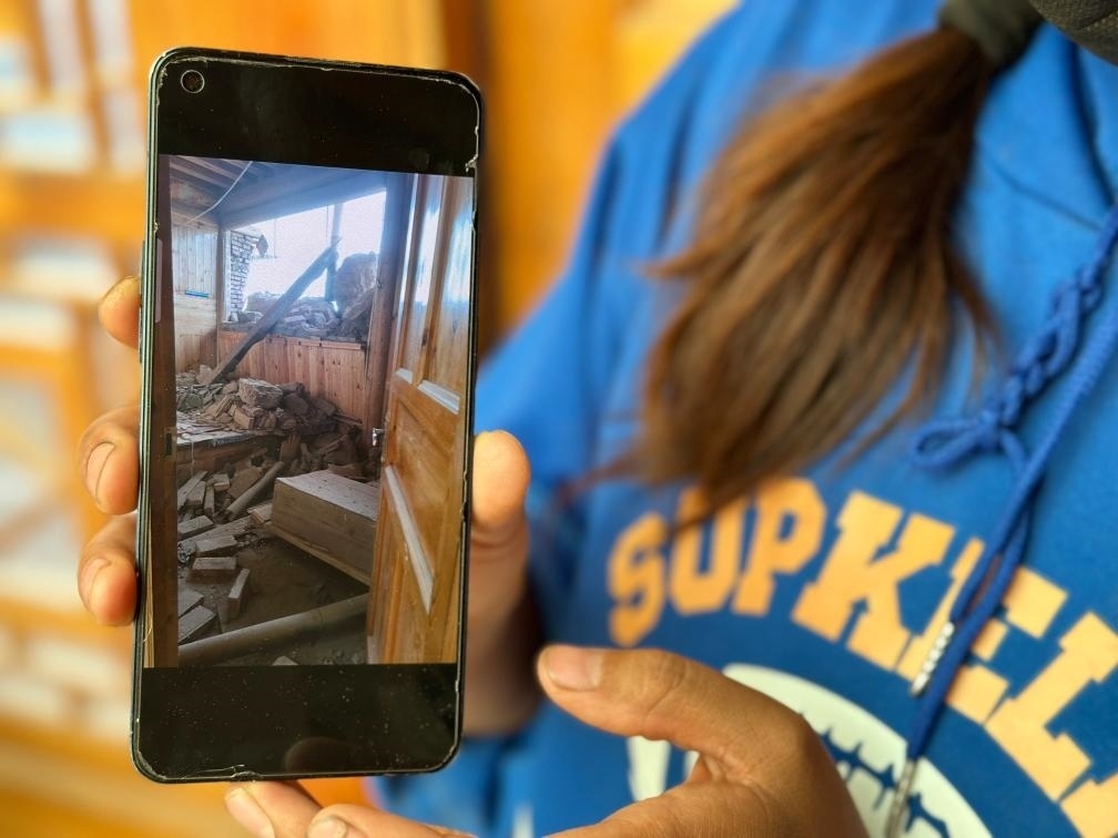 圖為7月17日拉毛東智在手機上找出地震后房屋受損的照片。新華社記者 張子琪 攝