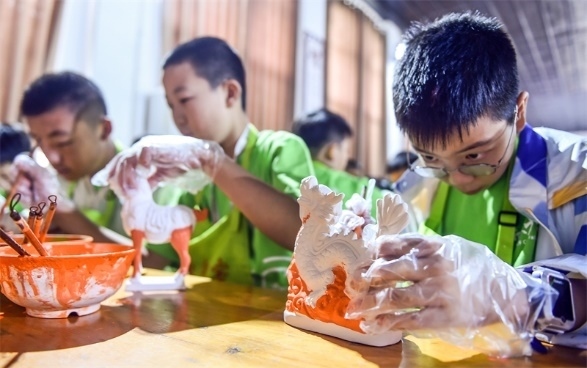 小朋友們?cè)诼尻柺忻辖騾^(qū)朝陽鎮(zhèn)南石山村體驗(yàn)唐三彩素胎施釉技藝。圖片來源：視覺中國(guó)