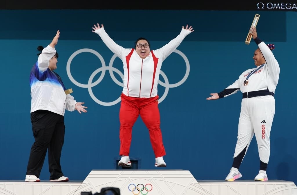 中國選手李雯雯（中）在巴黎奧運(yùn)會(huì)舉重女子81公斤以上級(jí)頒獎(jiǎng)儀式中登上領(lǐng)獎(jiǎng)臺(tái)（2024年8月11日攝）。新華社記者 楊磊 攝