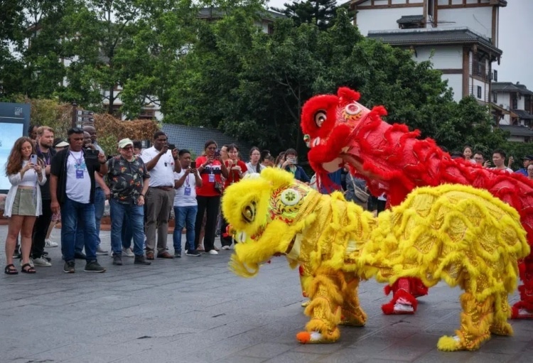 2024“一帶一路”媒體合作論壇聯(lián)合采訪調(diào)研行成員在樂山蘇稽古鎮(zhèn)觀看非遺舞獅表演。本報(bào)記者 伊霄攝