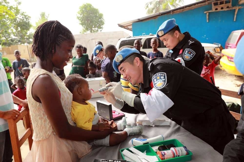 2017年12月28日，在利比里亞蒙羅維亞，中國維和警察防暴隊醫(yī)療人員為兒童做口腔檢查。