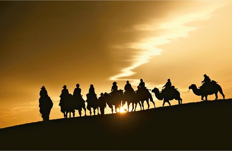 新時代以來，文化和旅游深度融合發(fā)展體制機(jī)制不斷健全，成功走出了一條獨(dú)具特色的中國旅游發(fā)展之路。圖為2024年9月1日清晨，游客在甘肅省敦煌市鳴沙山月牙泉景區(qū)乘騎駱駝，欣賞大漠風(fēng)光，體驗(yàn)絲路風(fēng)情。 新華社發(fā) 張曉亮/攝