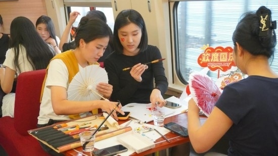 10月1日，旅客們在G1634次列車上給油紙傘作畫。新華社記者周義 攝