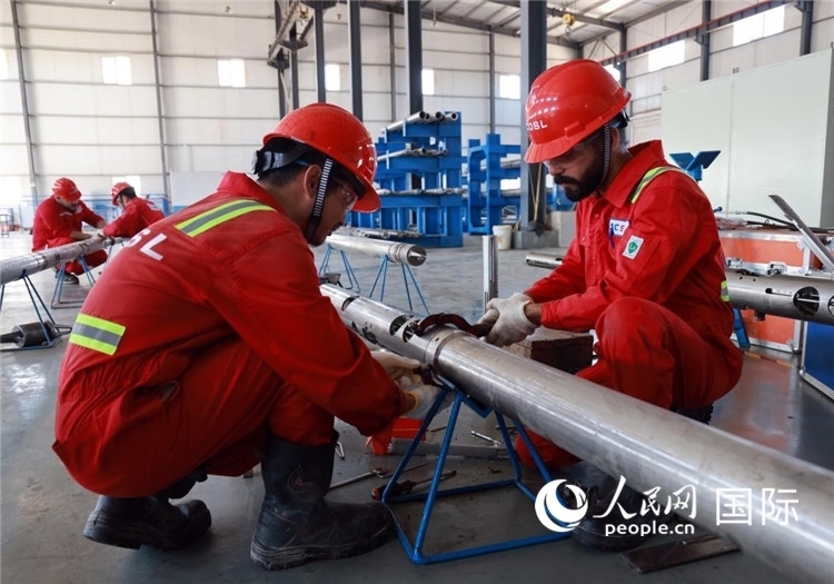 中伊員工共同在檢修鉆井設(shè)備。人民網(wǎng)記者管克江攝