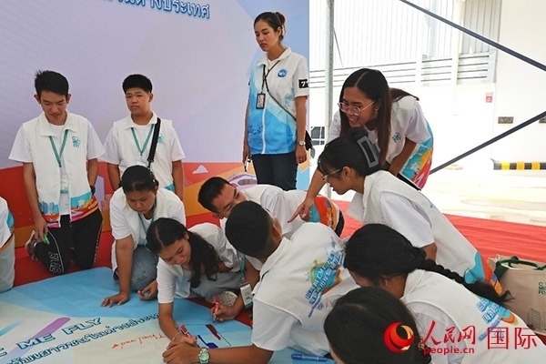 泰國學生在開營儀式展板上繪制圖案。人民網記者 白元琪攝