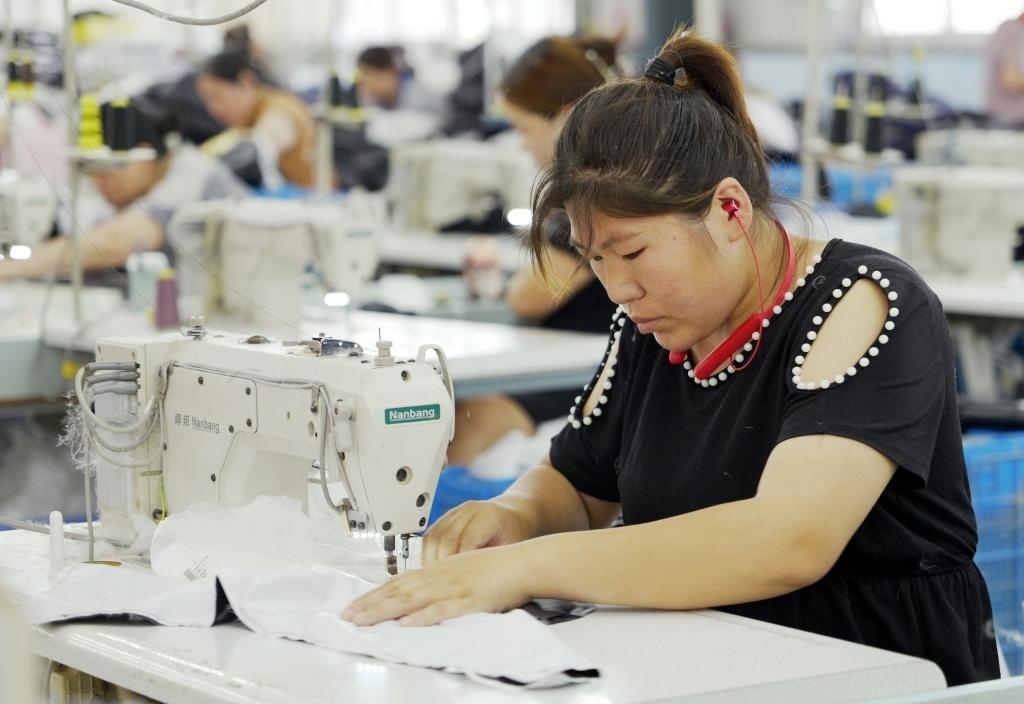 5月20日，村民在李寨村服裝加工廠內(nèi)忙碌。河南省周口市沈丘縣馮營(yíng)鎮(zhèn)李寨村地處豫東平原。近年來，乘著脫貧攻堅(jiān)與鄉(xiāng)村振興政策的東風(fēng)，李寨村積極探索產(chǎn)業(yè)發(fā)展模式，通過“龍頭企業(yè)+村集體經(jīng)濟(jì)+農(nóng)戶”的方式，逐漸發(fā)展形成肉牛養(yǎng)殖、設(shè)施農(nóng)業(yè)、服裝加工、康養(yǎng)民宿等產(chǎn)業(yè)，以產(chǎn)業(yè)振興助力鄉(xiāng)村振興。新華社記者 李嘉南 攝