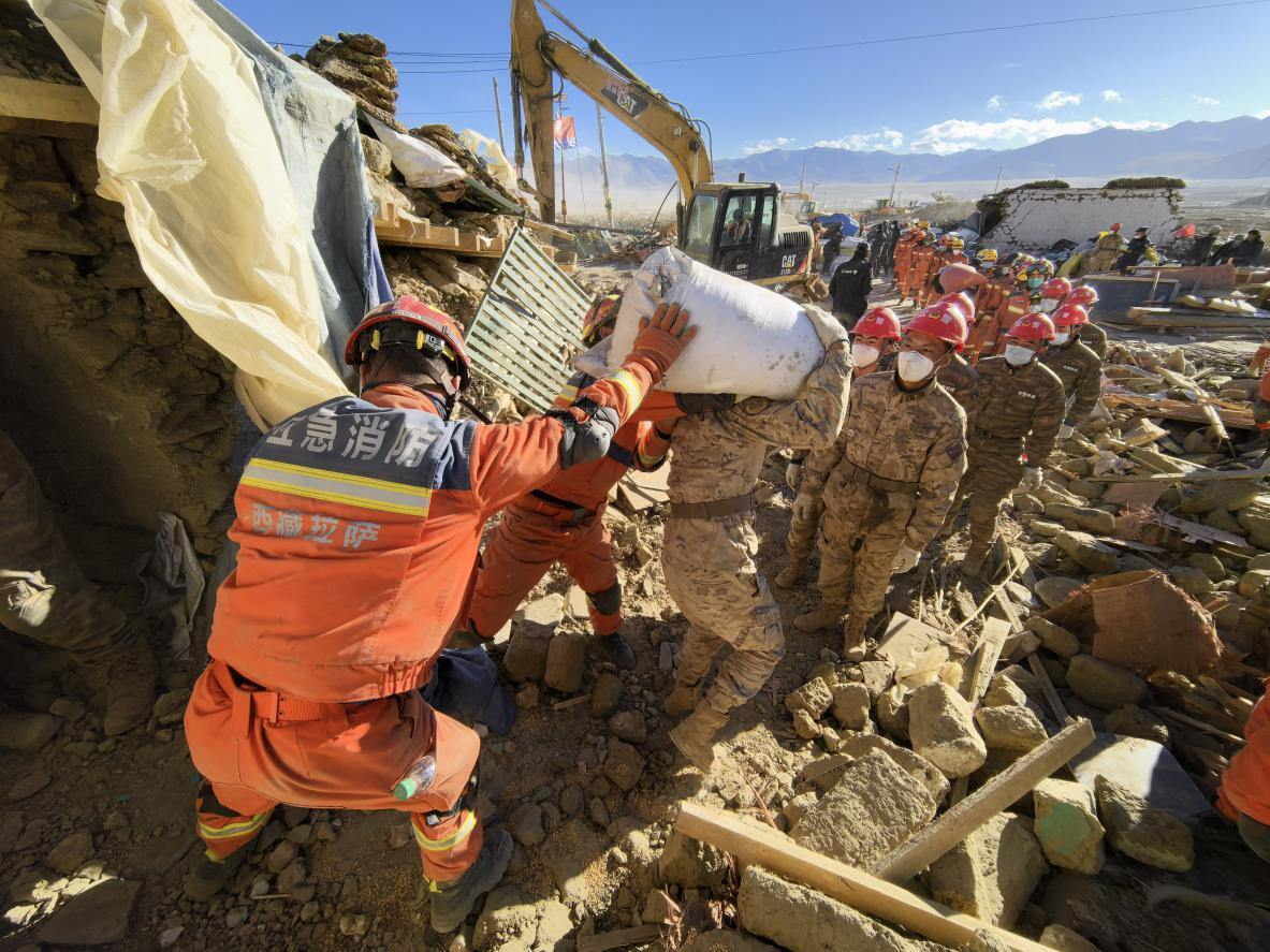 1月11日，定日縣長所鄉(xiāng)古榮村，應(yīng)急消防等救援人員排隊(duì)接力搶運(yùn)掩埋在倒塌房屋下的群眾財(cái)物。人民日報(bào)記者楊翹楚攝