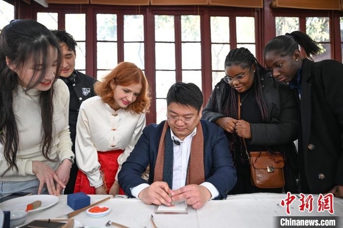 1月20日，篆刻家王臻向外籍留學(xué)生展示篆刻印章。當(dāng)日，來(lái)自巴西、馬來(lái)西亞、加納、哈薩克斯坦的外籍留學(xué)生在浙江杭州西泠印社體驗(yàn)福貼、春聯(lián)和篆刻，感受古老的中國(guó)傳統(tǒng)文化。中新社記者 王剛 攝