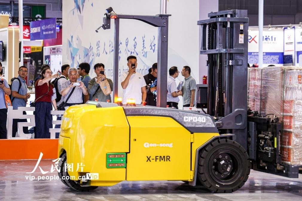 第24屆中國工博會現(xiàn)場，觀眾觀看叉取機器人作業(yè)演示。王初攝（人民圖片網(wǎng)）