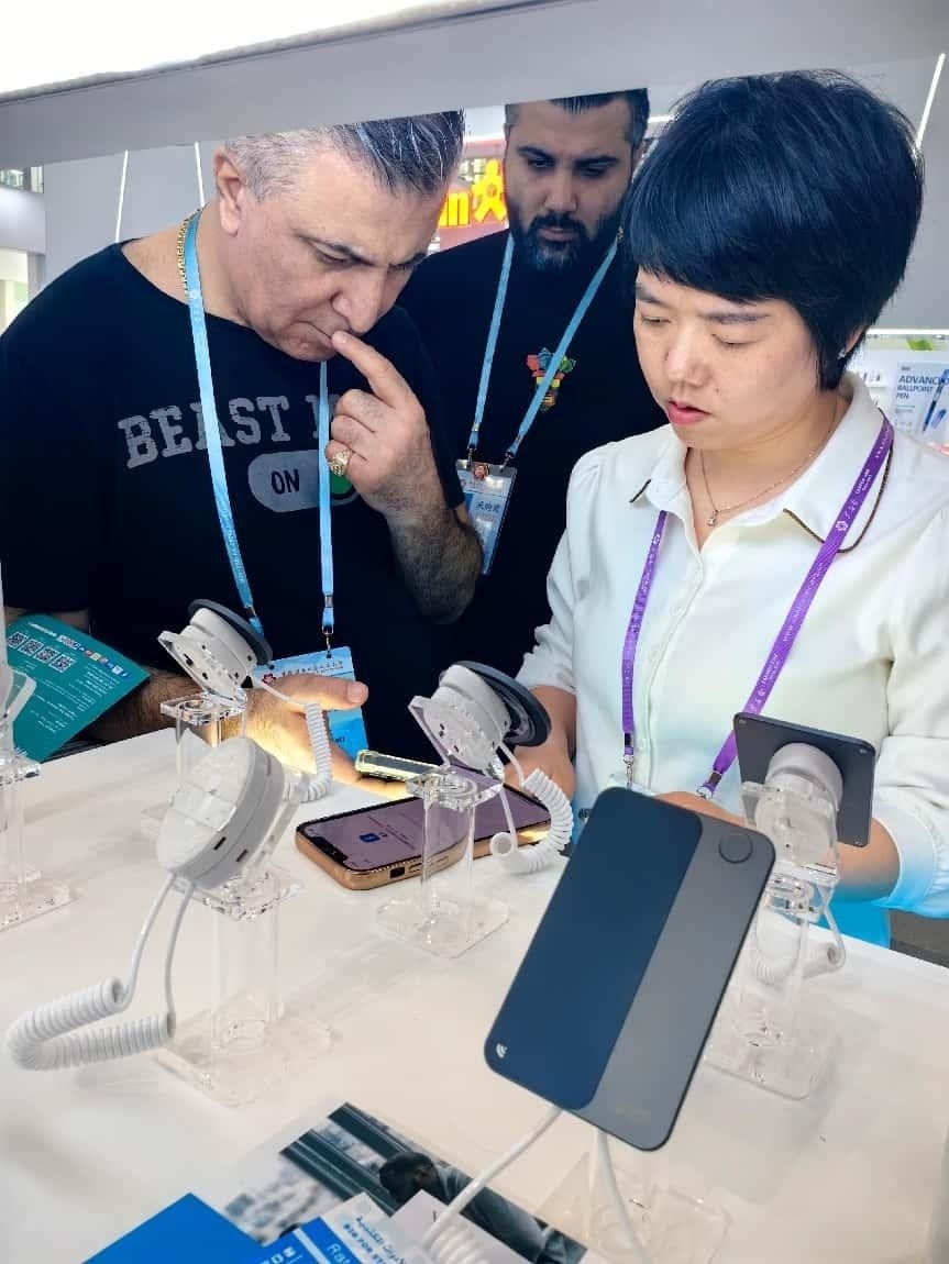 展臺(tái)工作人員向外商展示“AI TOP翻譯終端”。圖片來源：受訪者提供